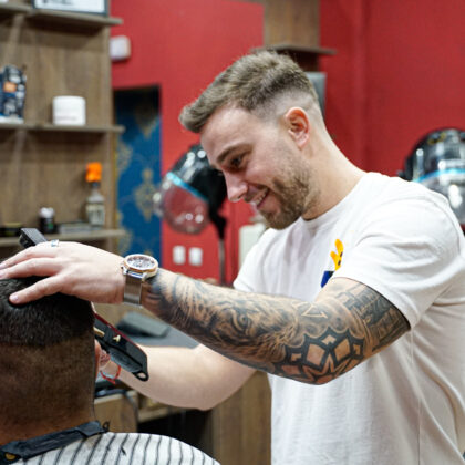 Barbero cortando el pelo y sonriendo